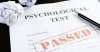 A piece of paper that says "Psychological Test" across the top and stamped on the middle of the page in red ink is the word "passed."