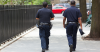 Two NYPD officers walking around in a neighborhood.